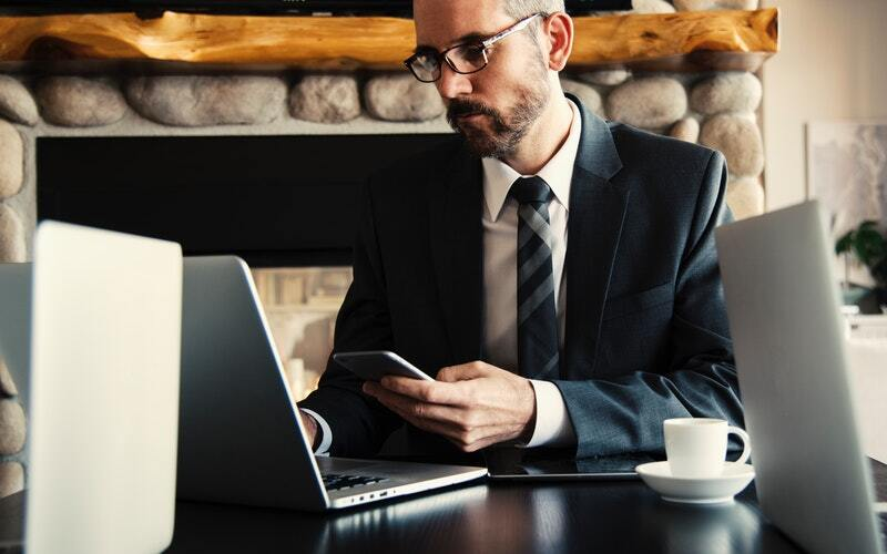 man using phone and laptop